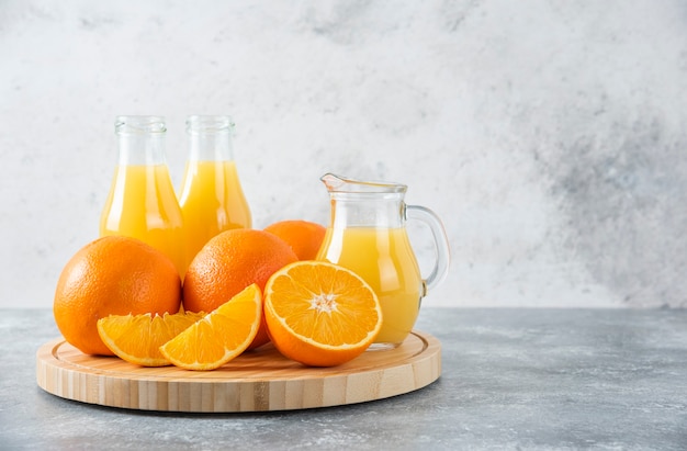 A wooden board full of juicy slices of orange fruit on stone table .