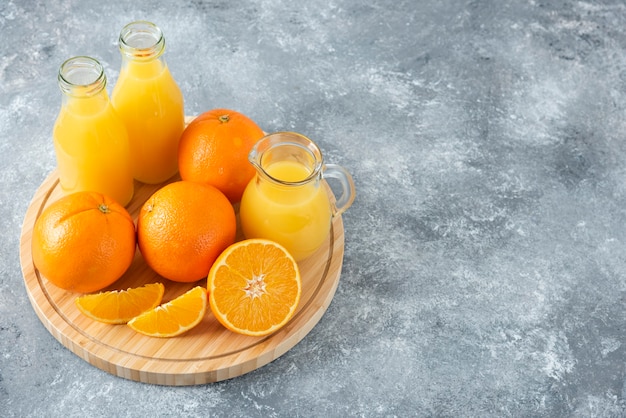 A wooden board full of juicy slices of orange fruit on stone table .