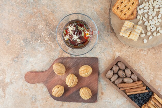 A wooden board full of sweet cookies and cup of herbal tea