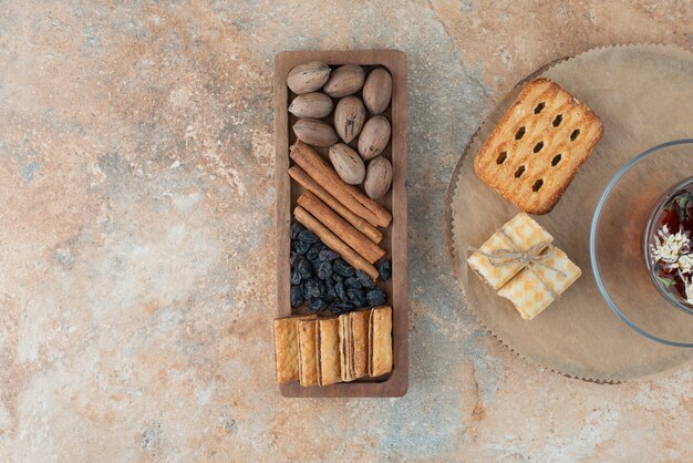 A wooden board full of sweet cookies and cup of herbal tea