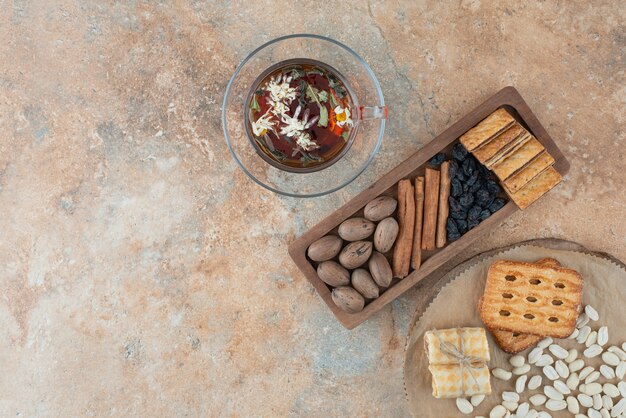 A wooden board full of sweet cookies and cup of herbal tea