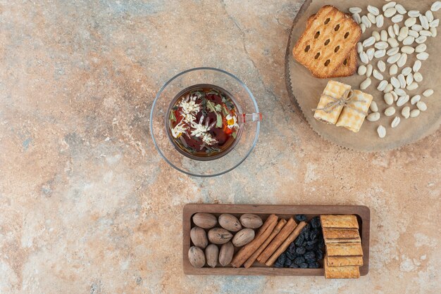 A wooden board full of sweet cookies and cup of herbal tea