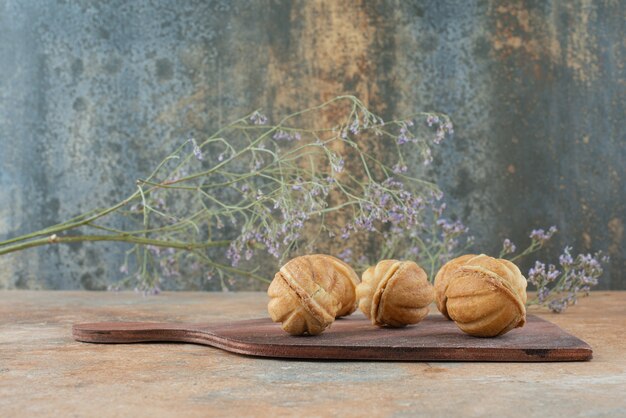 A wooden board full of sweet cookies on marble background