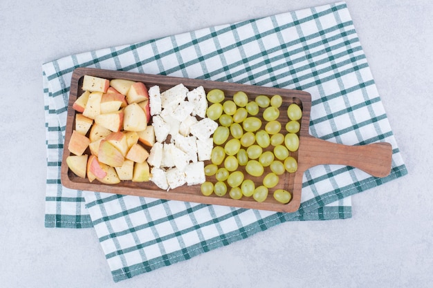 A wooden board full of white cheese and sliced fruits. High quality photo