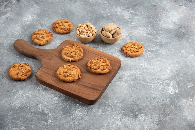 Wooden board of homemade cookies with organic peanuts on marble table. 