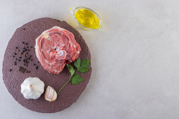 Free photo wooden board of raw meat with garlic and oil on table.