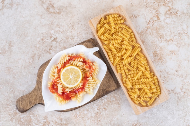 Free photo a wooden board of raw spiral macaroni and vegetables