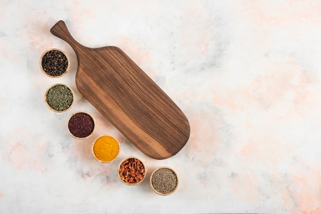 Wooden board and various kinds of spices on white background.