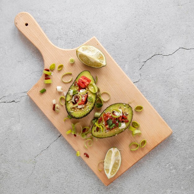 Wooden board with avocado salad on table