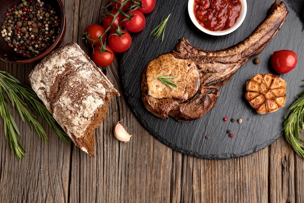 Wooden board with cooked meat and tomatoes