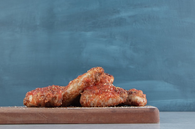 Free photo a wooden board with fried chicken meat with relish .