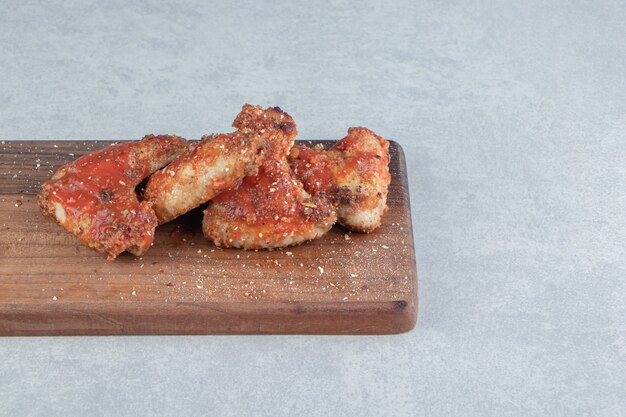 A wooden board with fried chicken meat with relish . 