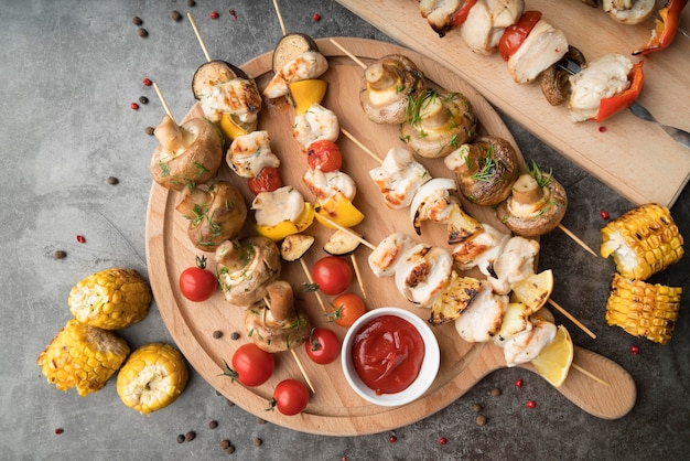 Wooden board with grilled chicken and vegetables skewers on table