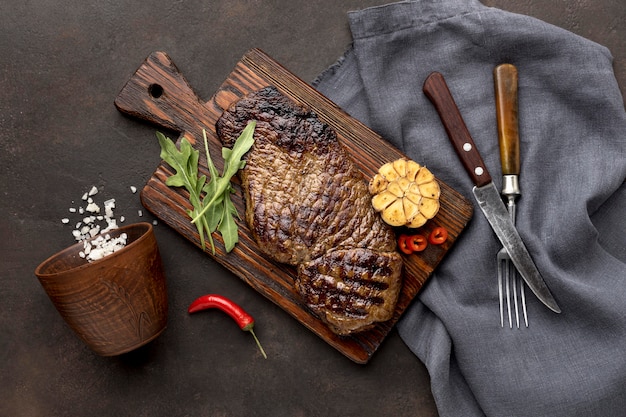 Free photo wooden board with grilled meat and cutlery