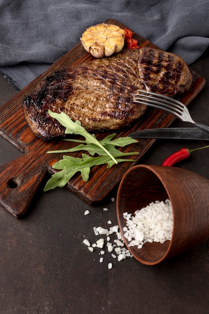 Wooden board with grilled meat on desk