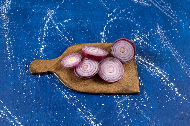 Free photo wooden board with purple onion rings on marble surface