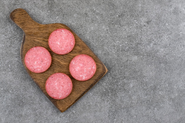 Free photo wooden board with sliced salami placed on stone table.