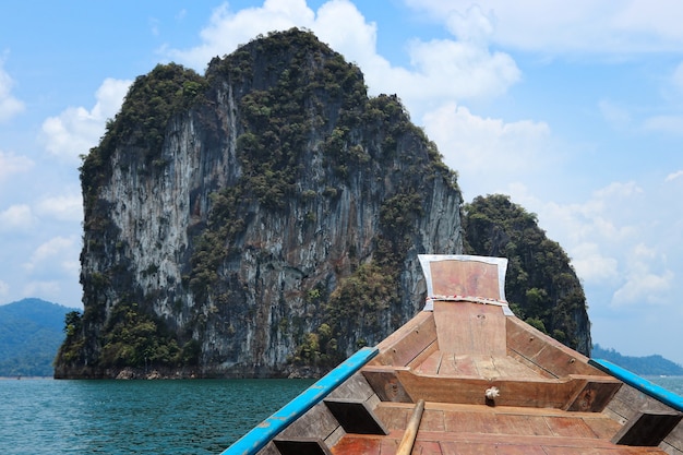 Free photo wooden boat on the sea surrounded by rock formations under a blue cloudy sky