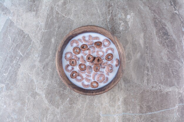 A wooden bowl of chocolate healthy cereal rings for breakfast . 