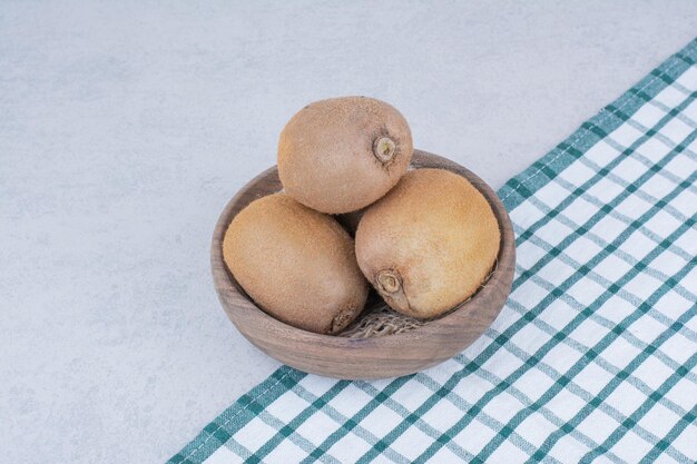 A wooden bowl of fresh kiwi on white background. High quality photo