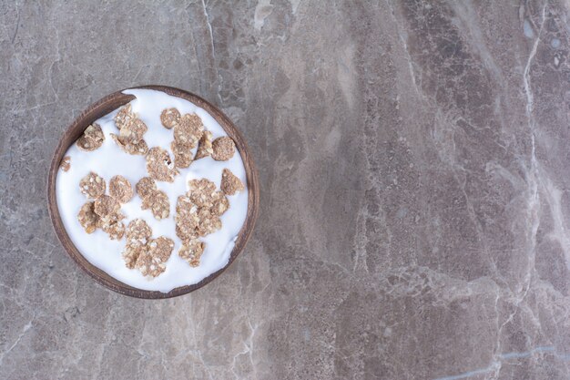 A wooden bowl full of healthy cereals with milk for breakfast. 