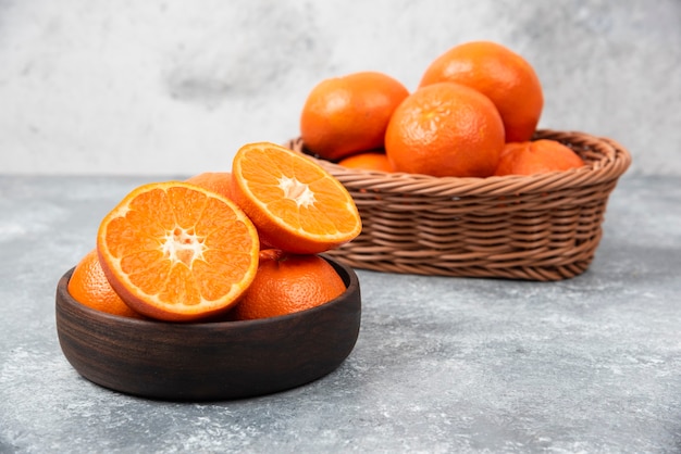 A wooden bowl full of juicy orange fruits on stone table .