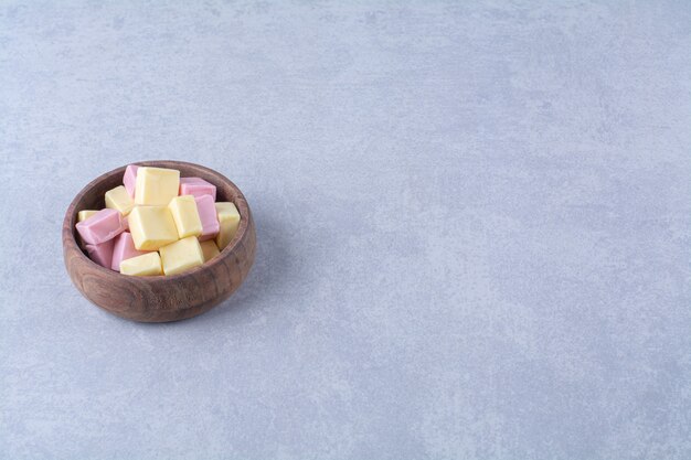 A wooden bowl full of pink sweet confectionery