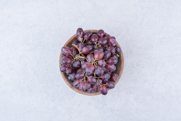 A wooden bowl full of purple grapes on white background . High quality photo