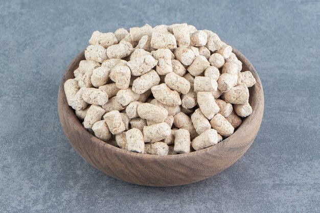 A wooden bowl full of rye crispy cereals .