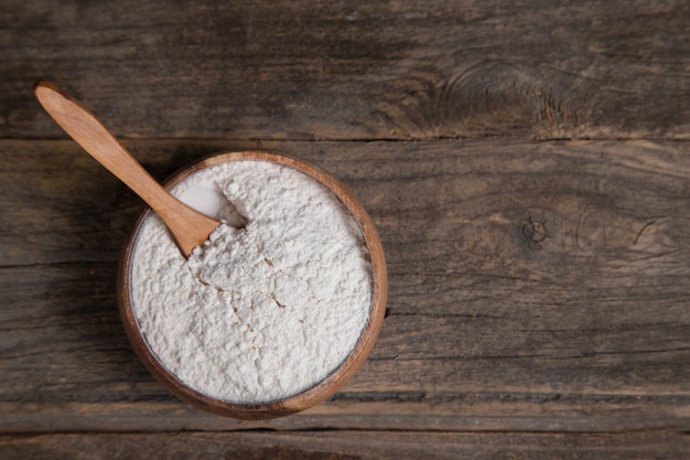 Wooden bowl of organic flour placed on wooden surface. High quality photo