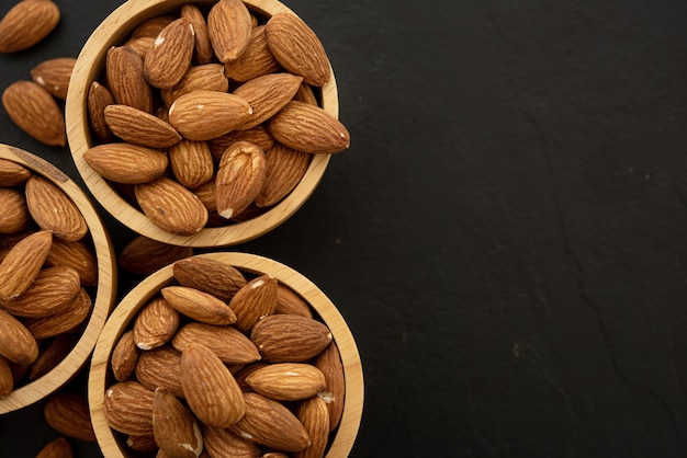 Free photo wooden bowl with almond on black background. top view.