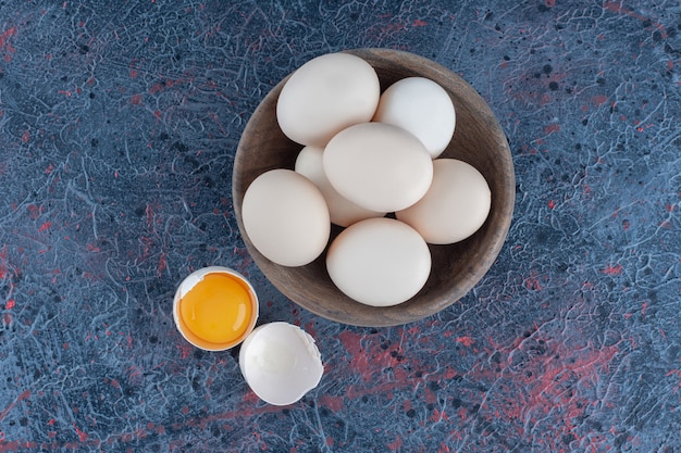 Free photo a wooden bowl with fresh raw chicken eggs .