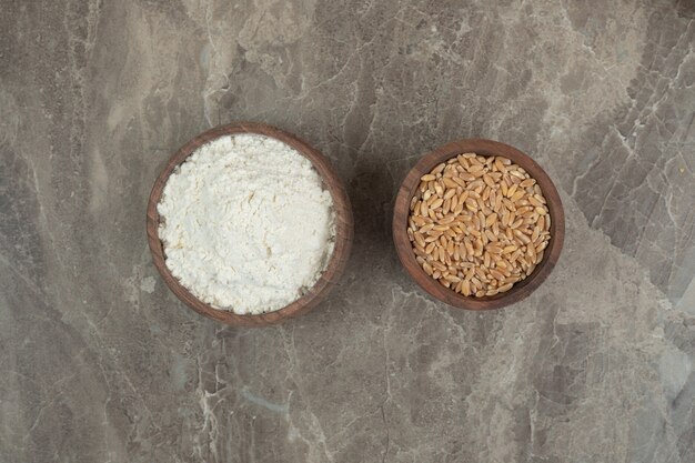 Wooden bowls of flour and barley on marble background. High quality photo