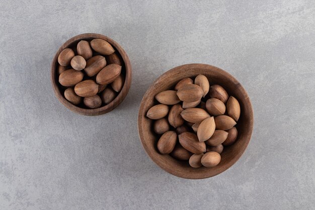 Wooden bowls of organic shelled walnuts on stone background. 