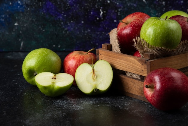 Wooden box of fresh organic apples on black surface. .