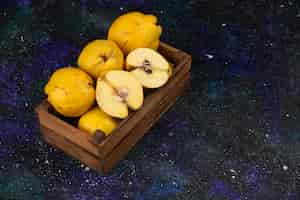 Free photo wooden box of fresh ripe quinces on dark table.