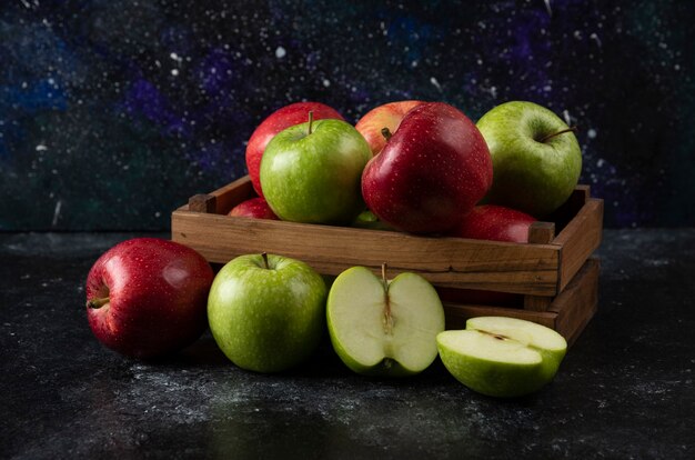 Wooden box of ripe organic apples on black surface. .