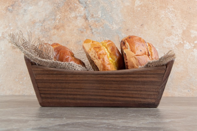 Wooden box of various tasty pastries on marble backgroudn