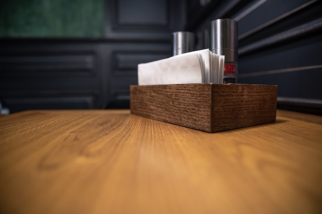 Wooden box with spices and napkins on a table in a cafe, close-up.