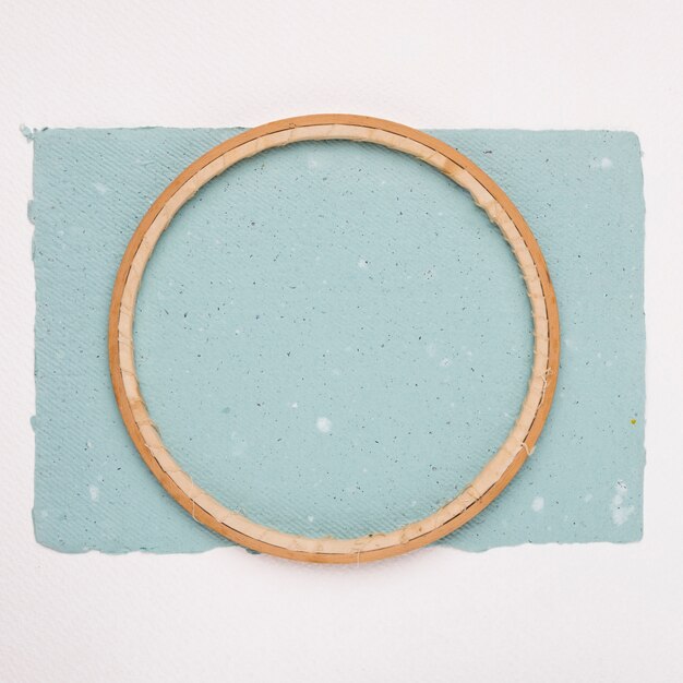 Wooden circular border frame on blue paper against white backdrop