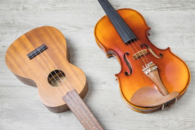 Wooden classical guitar and violin on textured backdrop