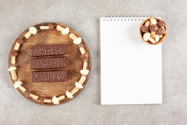 A wooden cutting board with three chocolates and sheet of paper.