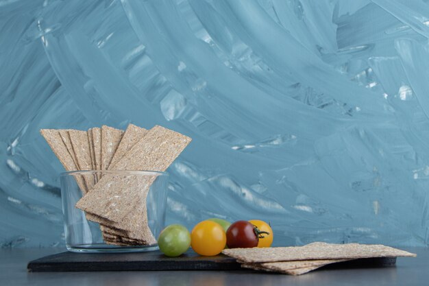 Free Photo a wooden dark board full of rye crispy cereals and colorful tomatoes .