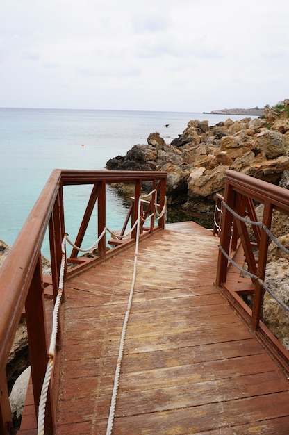 Free photo wooden dock near the ocean with a rocky coast