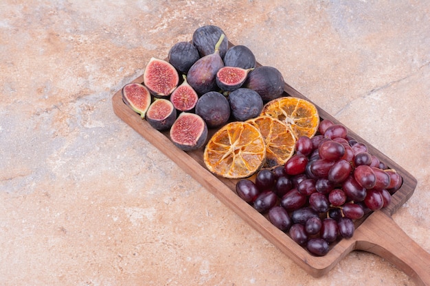 Wooden fruit platter with figs, corner berries and dry orange slices.