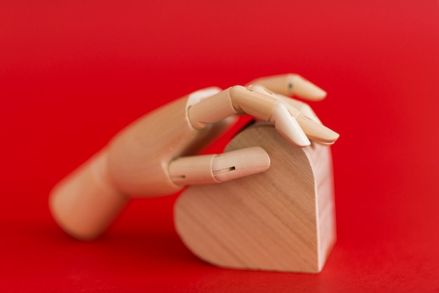 Wooden hand holding wooden heart on table 