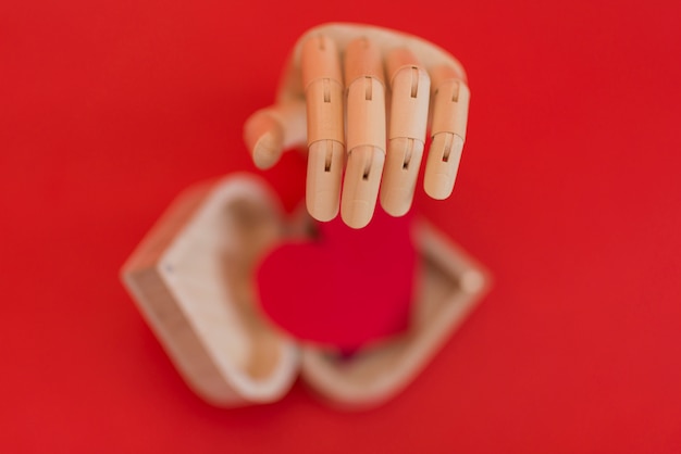 Wooden hand with red heart on table 