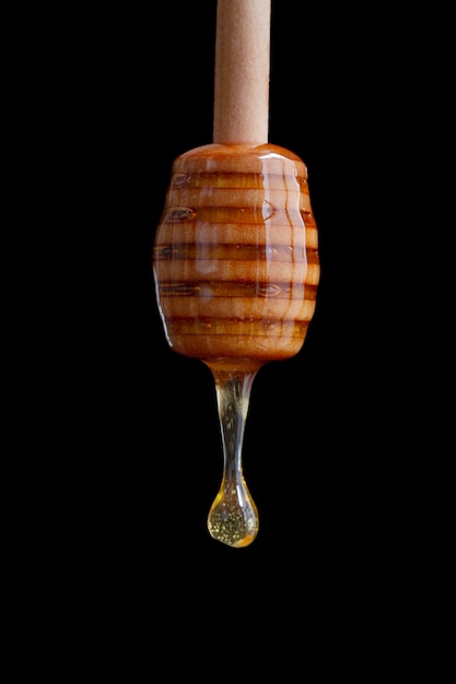 Free photo wooden honey dipper with dripping honey