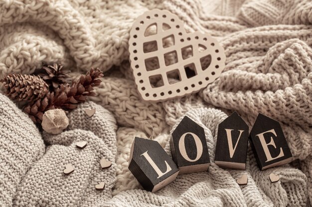 Wooden letters make up the word love on a background of cozy knitted items. 