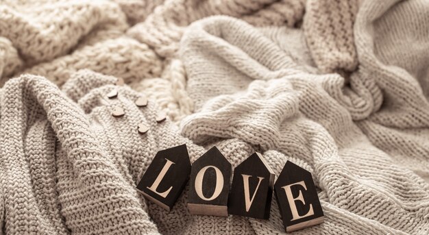 Free photo wooden letters make up the word love on a background of cozy knitted items.